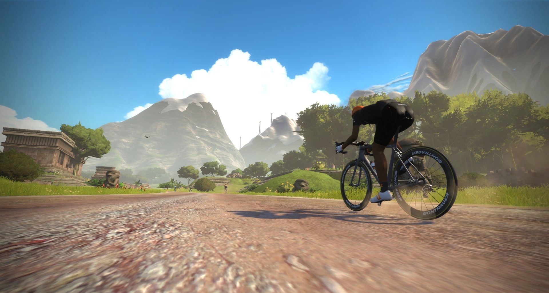 Zwift'te dağlar ve tapınak kalıntıları arasında, toprak yolda tek başına pedal çeviren bir bisikletçi